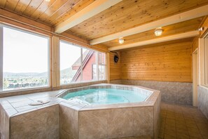 Relax in a spacious room with a large hot tub and a view of the surrounding landscape.