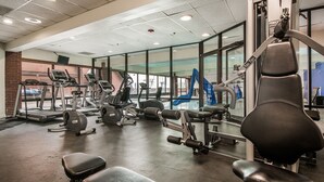 Une salle de sport équipée de tapis de course, d’appareils de musculation et de bancs.