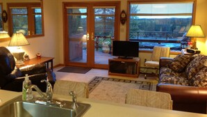 A living room with a sofa, a television, a coffee table, and a kitchen area with a sink.