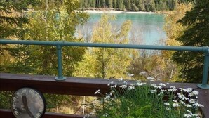 A view from a balcony with a clock, overlooking a lake surrounded by trees.