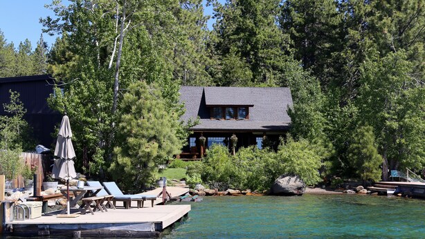 A lakeside cabin with a dock, surrounded by dense trees.