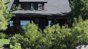 A lodge with a stone exterior, a dock, and a pond.