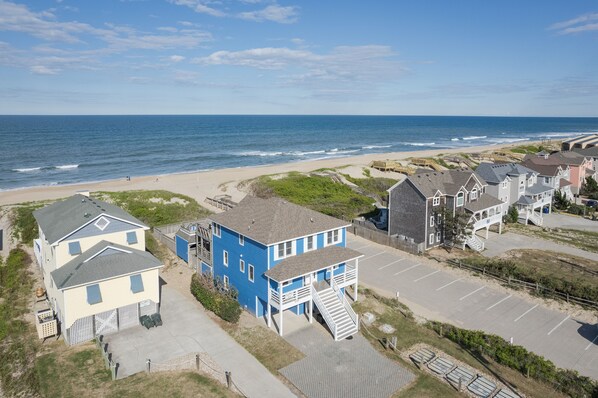 A coastal residential area with houses, a beach, and a parking lot. - 5514- Sisterly Love - Luxury Oceanfront | Pool, Hot Tub & Views (Nags Head)