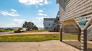 Un immeuble résidentiel à l’extérieur en bois, avec un escalier apparent et une enseigne indiquant qu’il propose des locations de vacances.