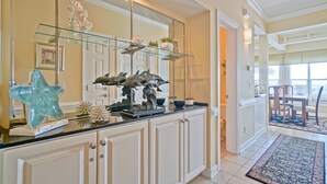 A kitchen with a glass shelf, white cabinets, and decorative items. - Gorgeous 4 BR/4 BA Top Floor Front Row Islander Villa (Ocean Isle Beach)