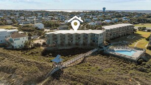 A beachfront hotel with multiple buildings, a swimming pool, and a pier leading to a beach. - 3196 - Sea Sights - Oceanfront Duck Condo | Walk to Duck Village (Duck)