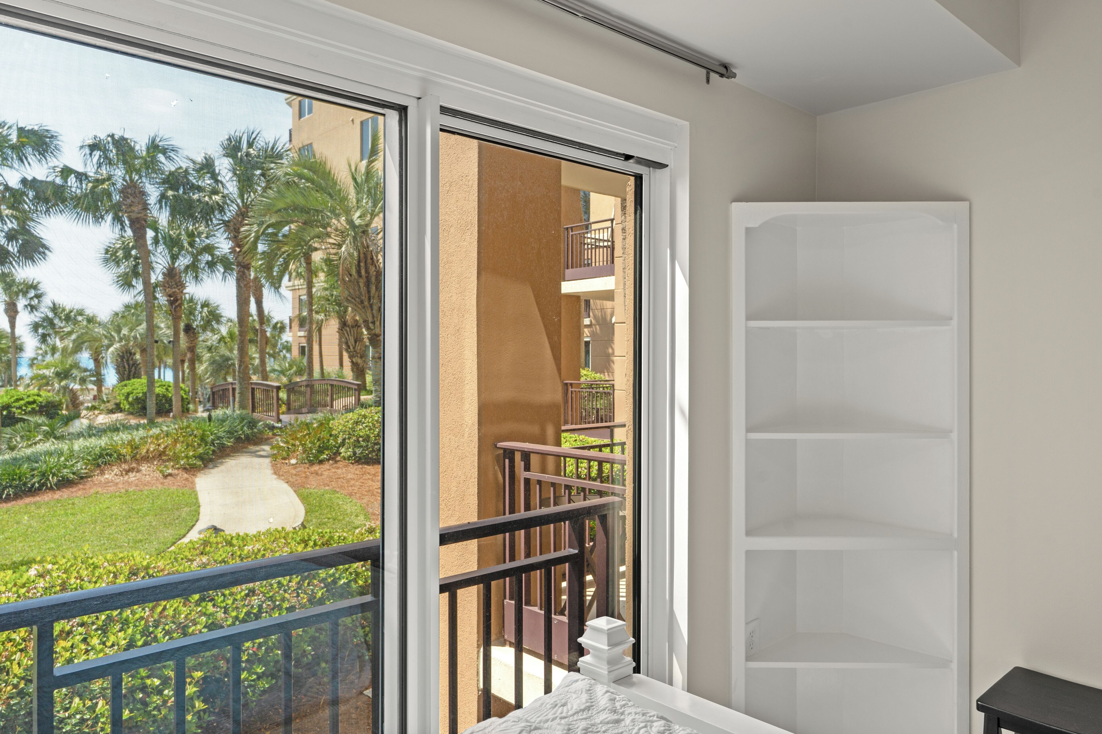 A balcony with a view of a landscaped garden and a building with balconies.