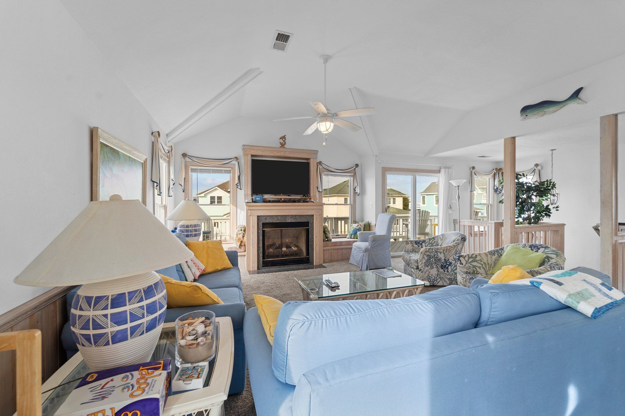 A spacious living room with a blue sofa, a fireplace, and a ceiling fan.