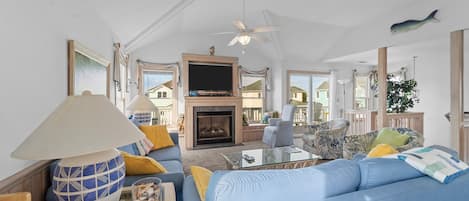 A spacious living room with a blue sofa, a fireplace, and a ceiling fan.