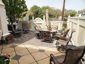Relax in the serene outdoor patio, featuring wicker chairs, a dining table, and a potted plant.