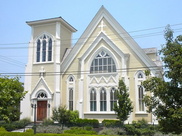 Stunning church with a prominent steeple and pointed arch window, set amidst a beautifully manicured lawn.