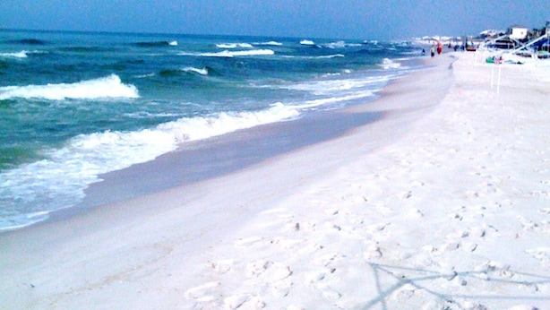 A beach with white sand and waves.