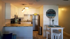 A modern kitchen with white cabinets, a stainless steel refrigerator, and a central island.