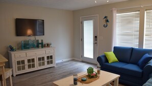 A living room with a TV, a blue couch, a white cabinet, and a wooden coffee table.
