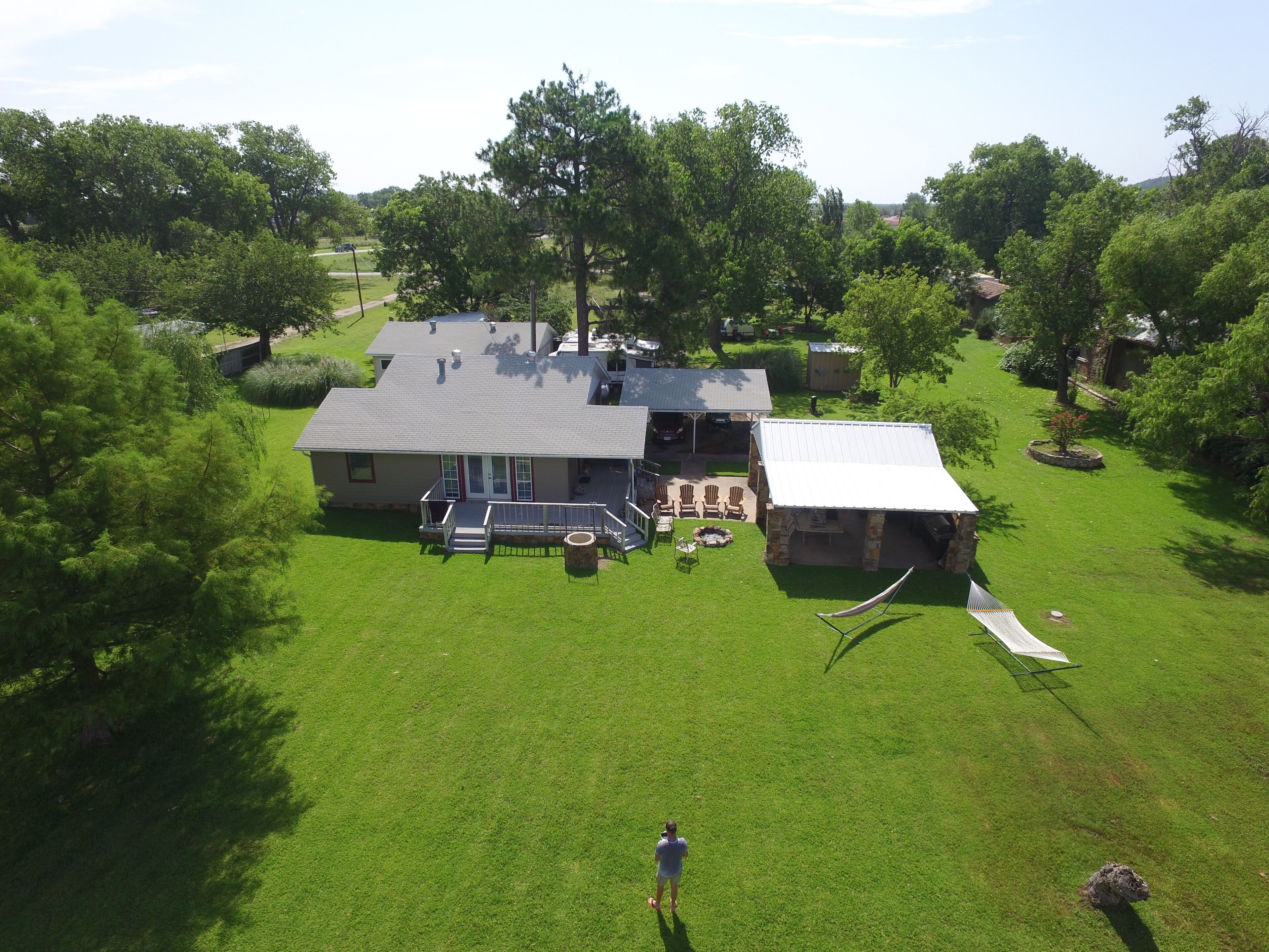 A house with a large lawn, a patio with outdoor furniture, and a small shed.