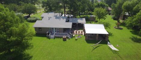 A house with a large lawn, a patio with outdoor furniture, and a small shed.