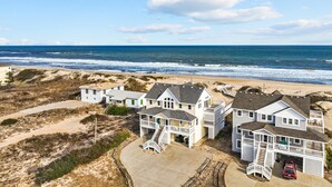Une propriété située en bord de mer, comprenant plusieurs maisons, une plage de sable et l’océan.