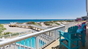 Une terrasse avec une piscine, une vue sur la plage et des chaises longues.