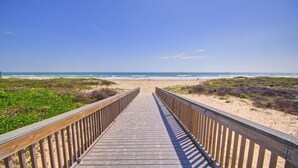 A wooden boardwalk leading to a beach with dunes and ocean views.