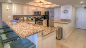 A kitchen with granite countertops, stainless steel appliances, and a built-in island.