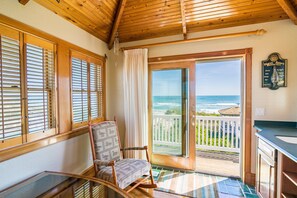 Una habitación con contraventanas de madera, una mecedora y vista al océano. Hay un cartel en la pared.
