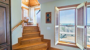Una escalera de madera que lleva a una terraza con vista al océano.