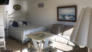 A bedroom with a bed, a desk, a chair, a sofa, and a ceiling fan.