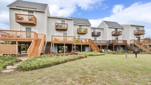 Un edificio residencial con varios balcones, terrazas de madera y un patio con césped.