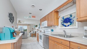 Una cocina moderna con gabinetes de madera, microondas, lavavajillas y un fregadero.