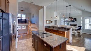 Une cuisine spacieuse dotée de plans de travail en granit, d’un grand îlot central et d’une cuisinière moderne.