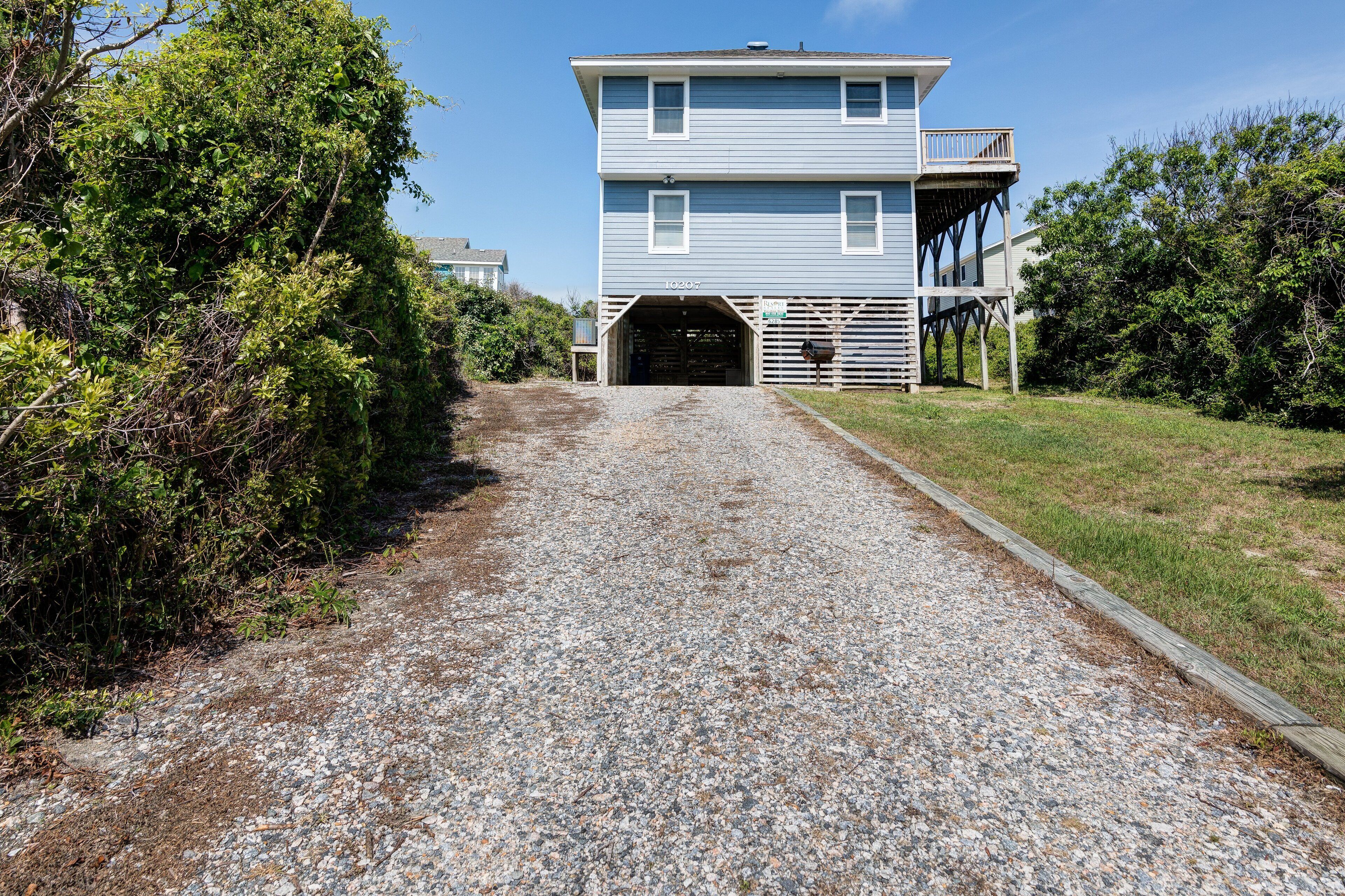 A two-story building with a gravel driveway leading to a garage.