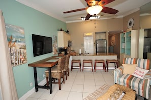 Relax in the stylish living and dining area, featuring a modern kitchen, comfortable sofa, and flat-screen TV.