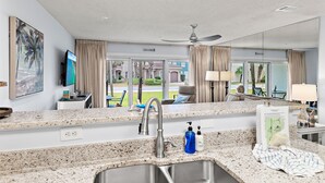 A hotel room with a kitchen area, a television, and a view of the outside.