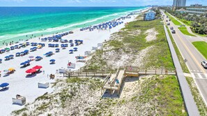 A beach with rows of umbrellas, a boardwalk, and a building in the background.