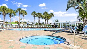 A swimming pool with lounge chairs and palm trees.