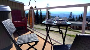 A balcony with two chairs, a table, and a view of mountains. - A Loft Above, Ski in/out, 3 Lofts, Private Hot Tub (Vernon)