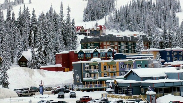 A snow-covered town with colorful buildings, a ski lift, and a parking area. - A Loft Above, Ski in/out, 3 Lofts, Private Hot Tub (Vernon)