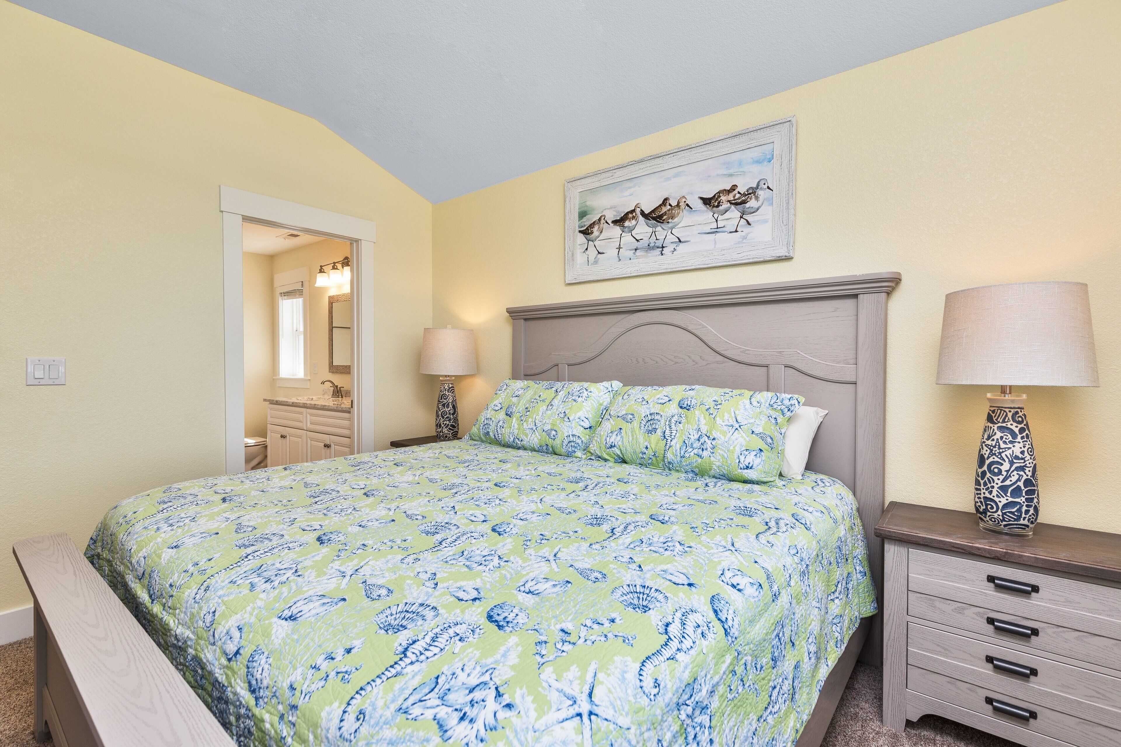 A bedroom with a bed, a nightstand, a lamp, a dresser, and a painting on the wall.