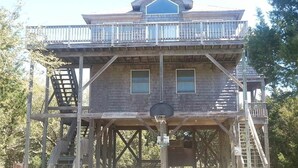 Una construcció de fusta de dos pisos amb un balcó, un cèrcol de bàsquet i una escala.