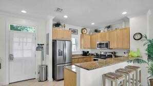 A modern kitchen with wooden cabinets, stainless steel appliances, and a central island with bar stools. - Waterfront Townhome with Boat Slip & Pool Access (Marathon)
