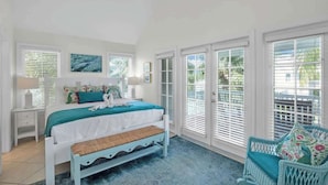 A bedroom with a bed, bench, chair, and a ceiling fan. - Waterfront Townhome with Boat Slip & Pool Access (Marathon)
