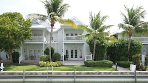 A large, two-story house with a balcony, surrounded by lush greenery and palm trees. - Waterfront Townhome with Boat Slip & Pool Access (Marathon)