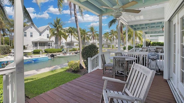 A covered outdoor area with a pool, wooden deck, and seating. - Waterfront Townhome with Boat Slip & Pool Access (Marathon)