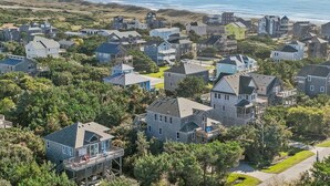 Een kustgebied met woonhuizen, omringd door groen, en een strand op de achtergrond.