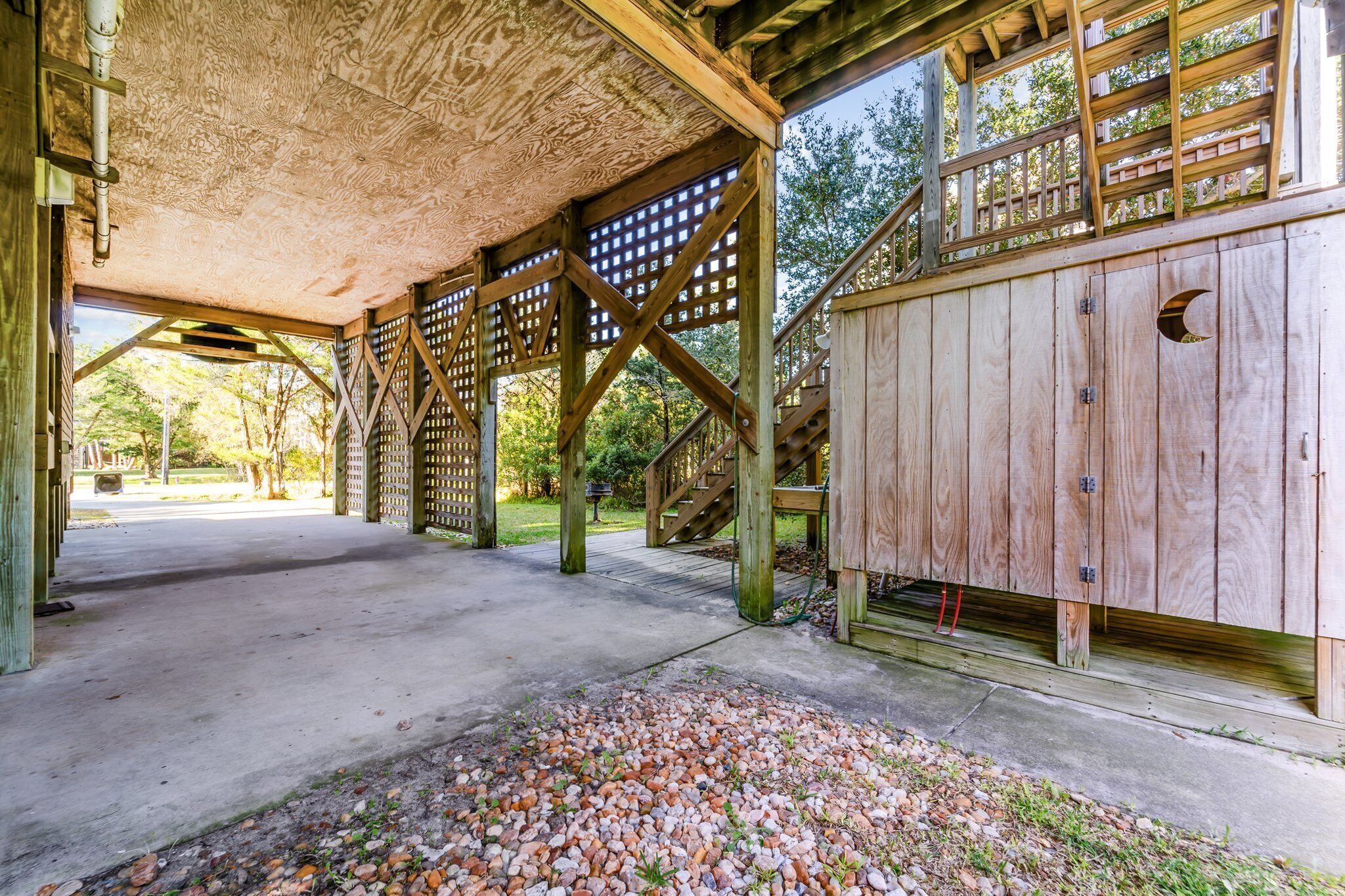 An open wooden structure with a concrete floor, wooden beams, and a lattice wall.