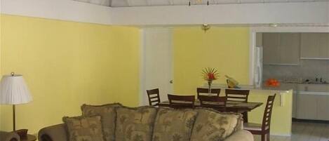 A spacious living room with a high ceiling, a ceiling fan, and a dining area with a table and chairs.