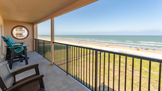 Ein Balkon mit Blick auf den Strand, einem runden Fenster und zwei Stühlen.