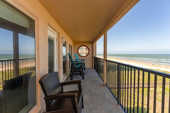 Enjoy the ocean view from this balcony with a table and two chairs.