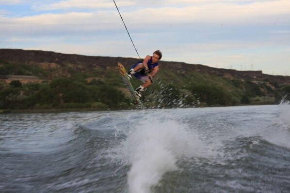A person wakeboarding on a river with a hilly landscape in the background. - The River Cabin - Hagerman, Idaho - Picture Postcard Beautiful! (Hagerman)