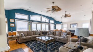 A spacious living room with a sectional sofa, a glass coffee table, and a large window offering a view of the city.